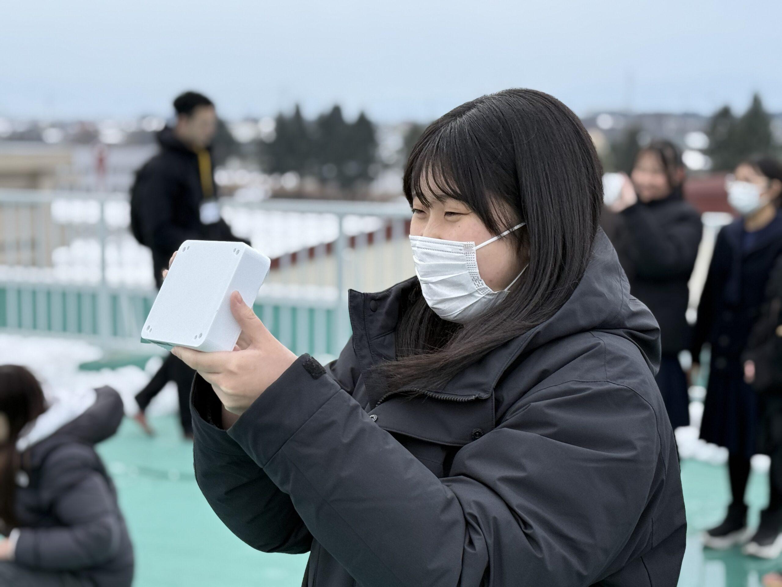 送信実験で高校生が通信機をYODAKAに向ける様子　※無線局の技術操作は無線従事者が実施